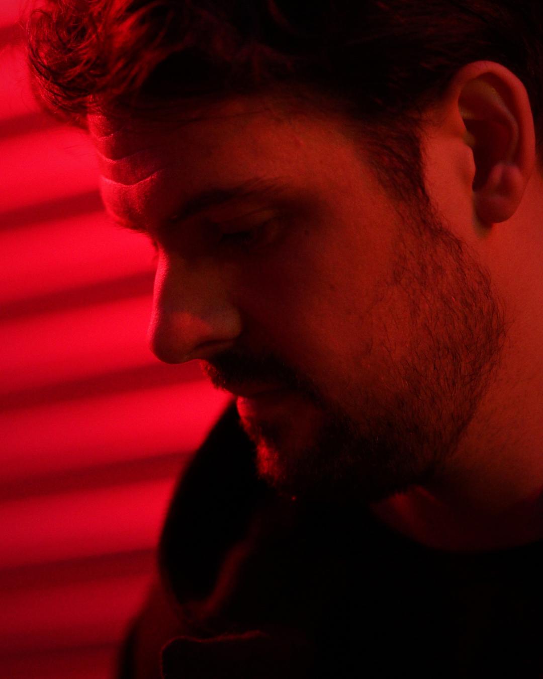 Adam, in profile, lit in red.
